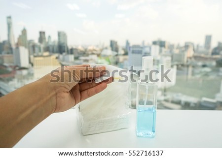 woman pull piece of tissue with alcohol bottle