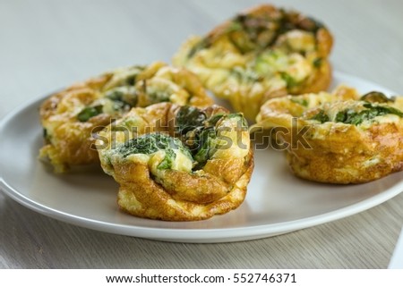 Gluten free savory muffin-like cake with spinach and broccoli on white wood table