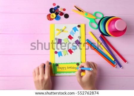 Female hands creating gift card on pink wooden background