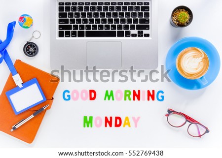 Caption word  Good morning Monday. White office desk with laptop, diary, eyeglasses, compass, pen, blank identification card and cup of coffee on white background.