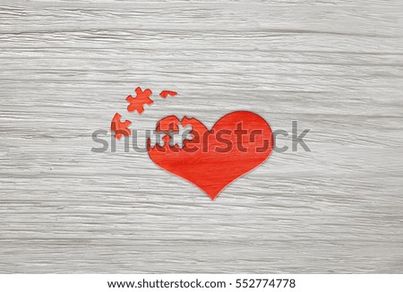 Red wooden puzzle heart on grey wooden background.