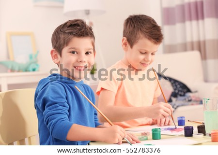 Cute little boys drawing pictures and sitting at table, closeup