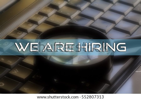 WE ARE HIRING word written on blur background of magnifier glass and laptop keyboard,conceptual