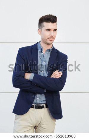 Portrait of serious young business man standing with arms crossed