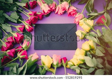 beautiful yellow and pink rose flowers and envelope with letter close-up on purple background