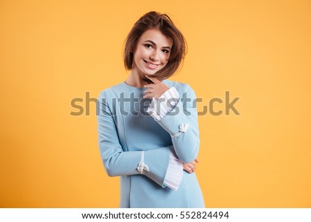 Portrait of happy beautiful young woman in blue dress over yellow background