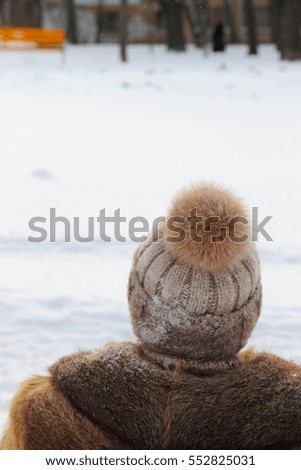 woman in a hat with pompon looks at snow
