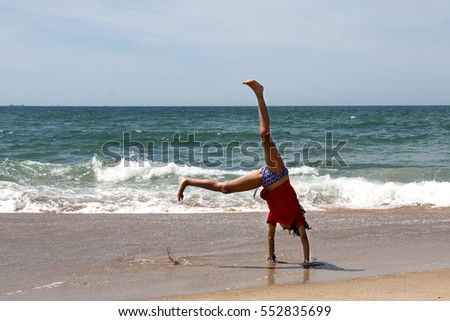 Cute young girl doing cartwheel at a beach in Brazil.