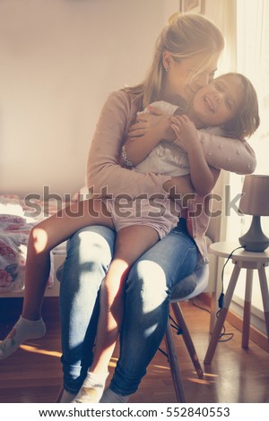 Mother hugging and kissing  her daughter.