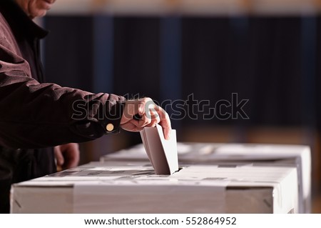 Hand of a person casting a vote into the ballot box during elections Royalty-Free Stock Photo #552864952