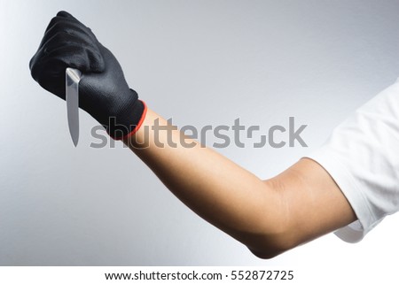 Hand with black grove holding a knife on white background