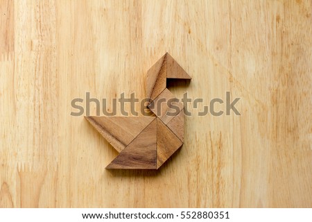 Tangram puzzle in swan shape on wooden background