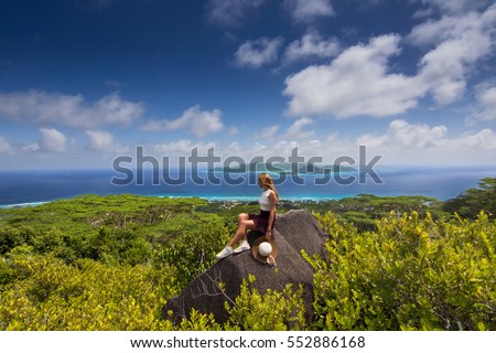 Girl who loves to travel sitting on top of the island watching the beautiful sea and tropical view of exotic destination from Seychelles / The highest point on La Digue , Nid d'Aigle Seychelles
