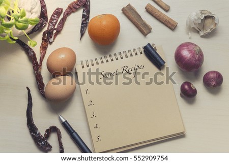Book with egg, onion and spices on wooden. word sweet recipes