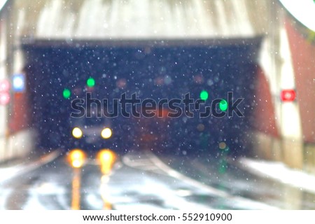 Abstract high key blurred image of car driving from tunnel under snow. Green street lights.