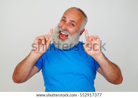 Senior stylish man with white beard is posing at the camera expressing happiness and joy against white background