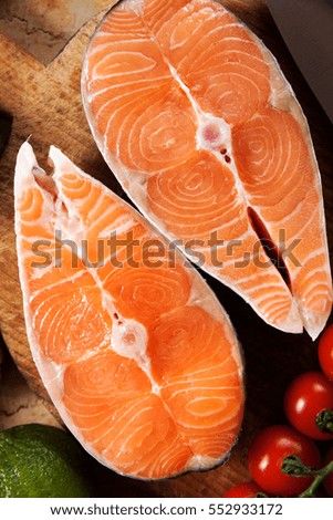 Two fresh raw salmon steaks with tomatoes on marble table