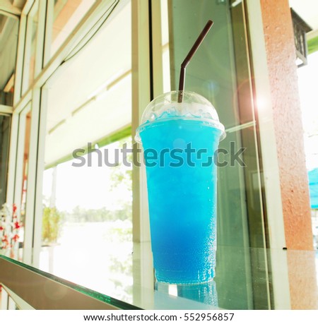 blue Hawaii soda beside mirror window in coffee shop with flare light 