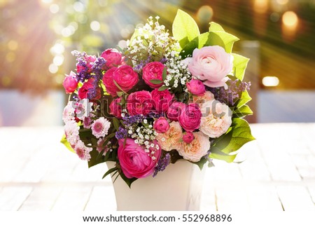 Colorful spring bouquet on a wooden table with sunrays and bokeh