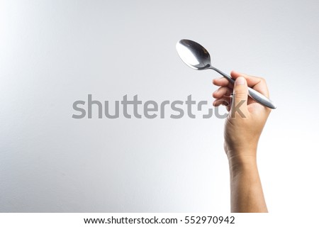 Man hand holding a silver spoon on white background Royalty-Free Stock Photo #552970942