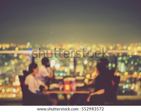 Blurred focus of rooftop restaurant with people dinning at night, vintage filtered Royalty-Free Stock Photo #552983572