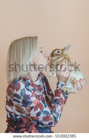 Female kissing rabbit on warm background