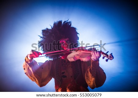 Venetian masquerade violinist playing the violin in smoke and darkness.
