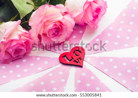 Three beautiful roses and red wooden figure of heart on pink and white background. St. Valentine's day