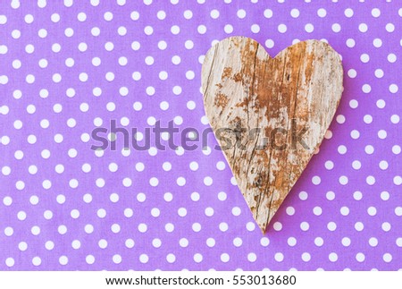 Romantic wood heart on purple white dotted fabric background, lovely greeting card with copy space.