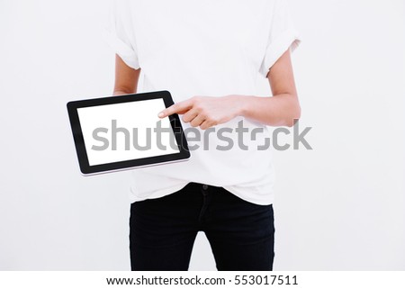 Girl points a finger at the screen of the tablet. On a white background. Close up.