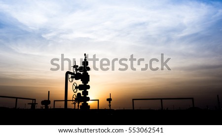 Silhouette of wellhead assembly on oil well in oilfield Royalty-Free Stock Photo #553062541