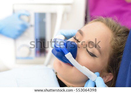 Beautiful getting woman inhalation sedation at dental clinic Royalty-Free Stock Photo #553064398