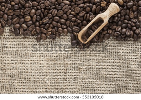 Coffee beans with wooden scoop on canvas. image with copy space