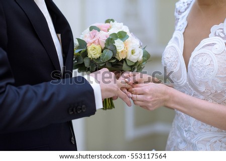 Beauty bride and handsome groom are wearing rings each other. Wedding couple on the marriage ceremony. Beautiful model girl in white dress. Man in suit. Female and male portrait. Cute lady and guy