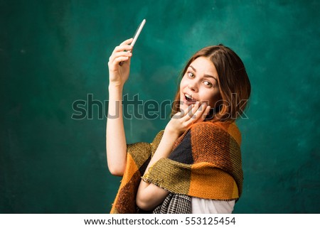 Inspired joyful woman with mobile smartphone in hand isolated on green.Girl making selfie