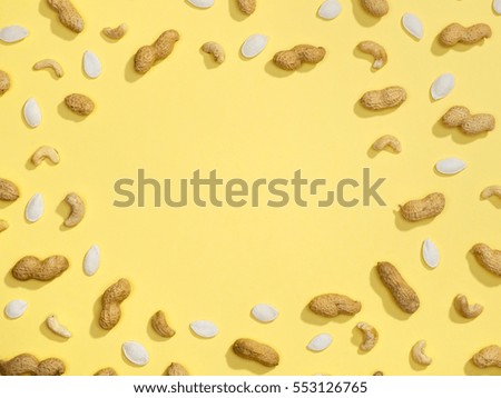 Peanut, pumpkin seeds and cashews flat lay frame on yellow background