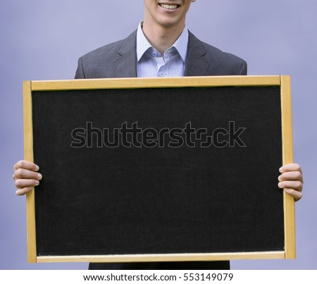young man in suit holding up a black chalkboard 