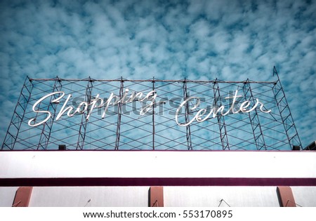 neon shopping center sign and cloudy sky                              