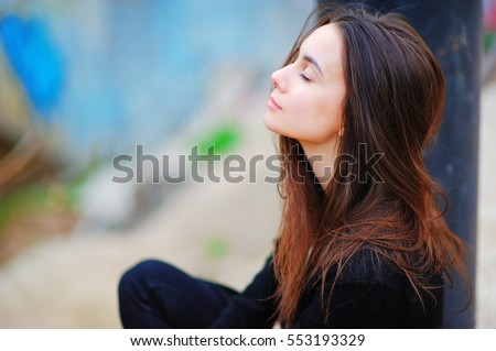 Portrait of a dreamy cute happy woman worker meditating outdoors with big eyes closed, sitting with the effect of blur closeup. De stress relief fit exercise, easy train enjoy career rest time concept Royalty-Free Stock Photo #553193329