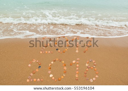 Happy New Year 2018 concept: The waves are about to cover 2017, both years placed with seashells on the beach