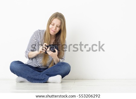Confused young blonde girl does not understand how to make photos on her camera. Photography training.