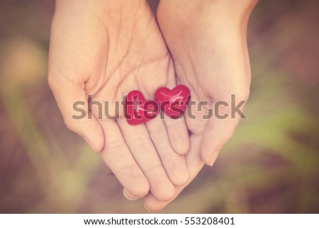 Two small red heart on female hands