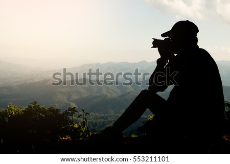 Silhouette of a young who like to travel and photographer, taking pictures of the beautiful moments during the sunset ,sunrise and mountain