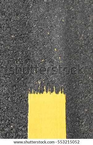Close up view of the above background, the yellow line is painted on the asphalt surface.