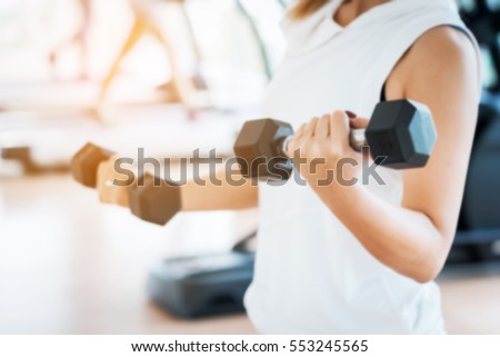 Blurred Woman Lifting Dumbbells in Weight Training Fitness - Sport and Lifestyle Concept Royalty-Free Stock Photo #553245565