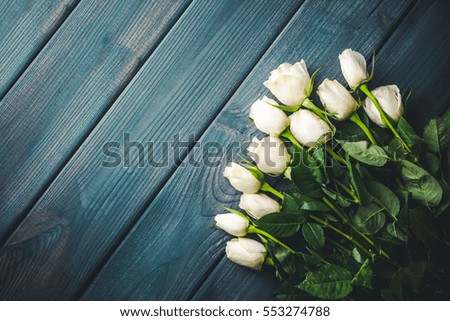 White roses on blue desks wooden background. 