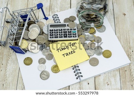 Shopping chart, coins, calculator and TIME FOR TAXES wording on wooden table.