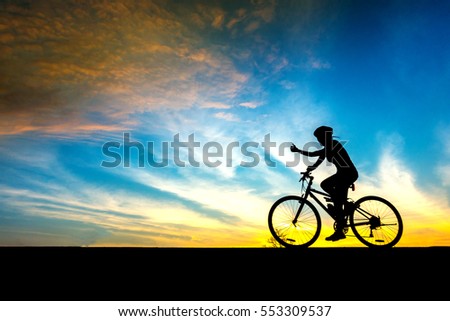 Woman cyclist and Bicycle silhouettes on the dark background of sunsets