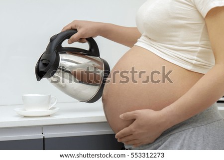pregnant woman hand hold electric pot and hold her belly