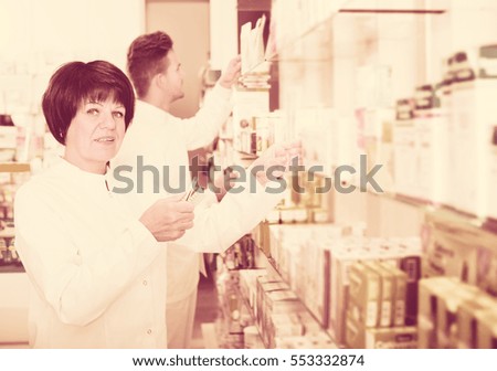 Friendly adult team of pharmaceutist and technician working in chemist shop